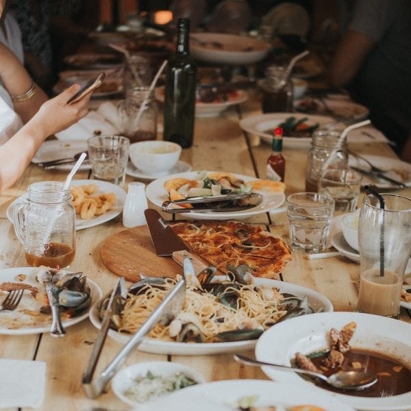 Someone using their mobile phone at a table surrounded by dirty dishes